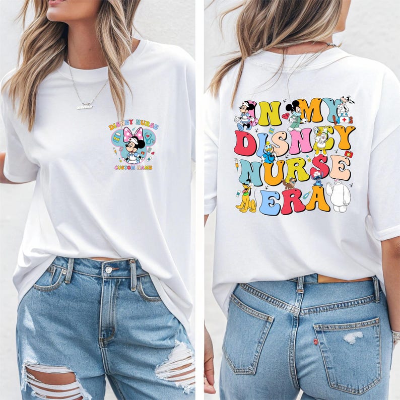 May include: White t-shirt with a colorful graphic on the front featuring Minnie Mouse in a nurse's uniform and the text "Disney Nurse". The back of the shirt has the text "In My Disney Nurse Era" with various Disney characters.