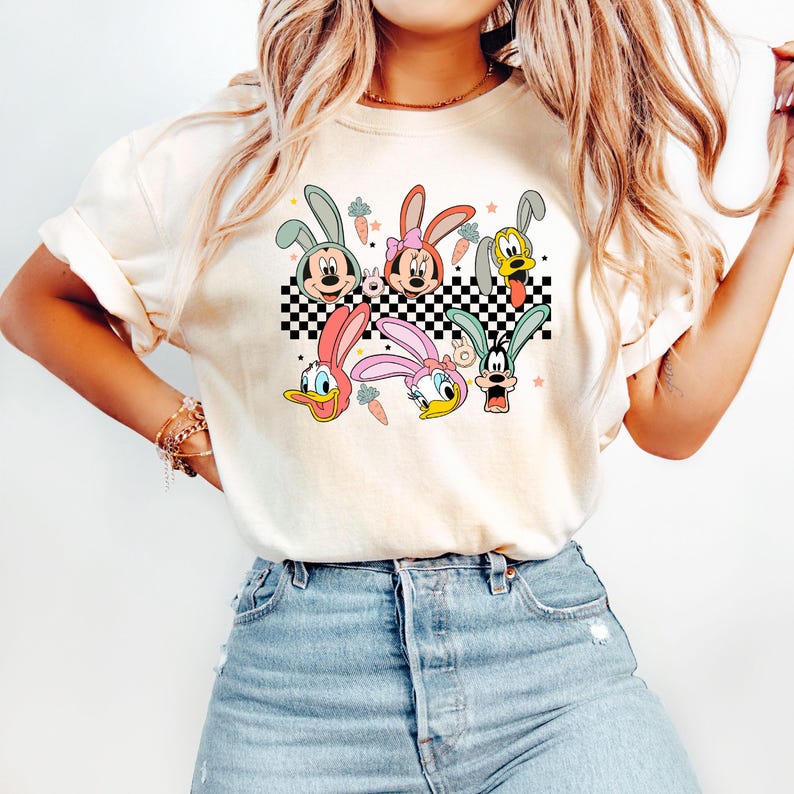 May include: A white t-shirt with a checkered pattern and cartoon characters wearing bunny ears. The characters include Mickey Mouse, Minnie Mouse, Donald Duck, Daisy Duck, and Goofy.