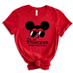 May include: Red t-shirt with a black Mickey Mouse wearing sunglasses and the text "Princess Protection".