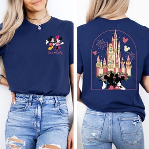 K&ouml;nnte beinhalten: Ein marineblaues T-Shirt mit einem Mickey Mouse und Minnie Mouse Motiv auf der Vorderseite und einem Motiv von Schloss Aschenputtel mit Mickey Mouse und Minnie Mouse auf der R&uuml;ckseite. Der Text "Jack &hearts; Emily" ist unter dem Mickey Mouse und Minnie Mouse Motiv auf der Vorderseite gedruckt.