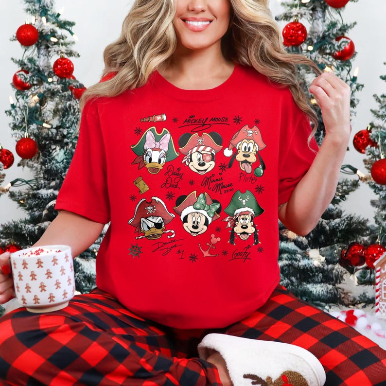 May include: Red short-sleeved t-shirt featuring cartoon characters in pirate hats. The shirt includes images of Mickey Mouse, Donald Duck, Minnie Mouse, Goofy, and Pluto. The text "Mickey Mouse" is printed at the top.
