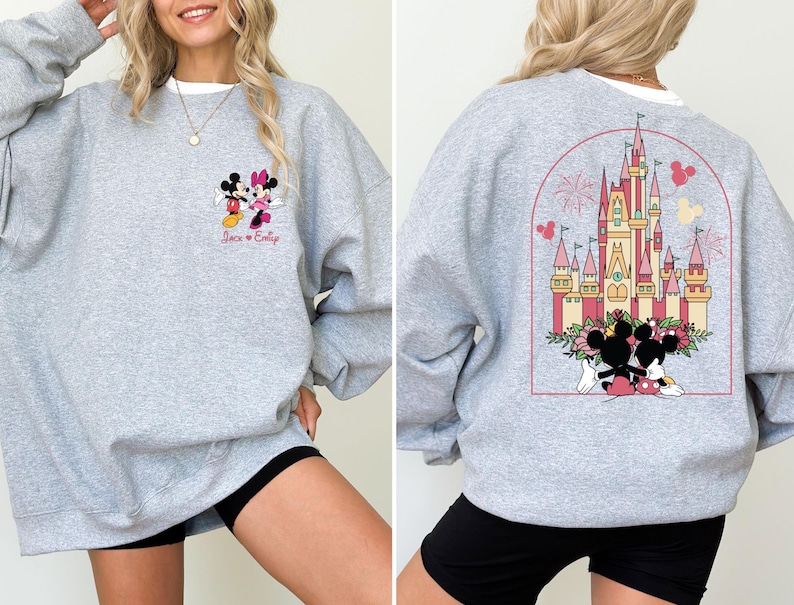 K&ouml;nnte beinhalten: Grauer Pullover mit einem Mickey Mouse und Minnie Mouse Motiv auf der Vorderseite und einem Motiv von Schloss Aschenputtel mit Mickey Mouse und Minnie Mouse auf der R&uuml;ckseite. Der Text "Jack & Emily" ist unter dem Mickey Mouse und Minnie Mouse Motiv gedruckt.