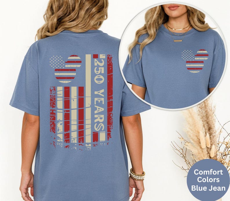 May include: Blue jean-colored t-shirt with a distressed American flag design. The back features a large flag graphic with the text "250 YEARS". The front has a smaller flag design. The shirt is a comfort colors style.