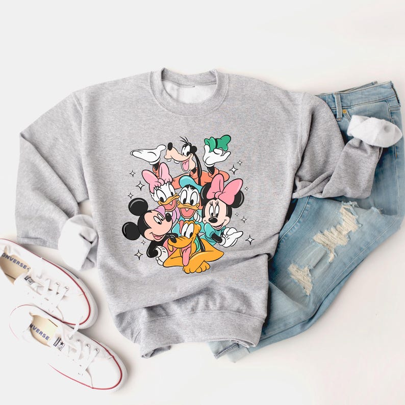 May include: A gray sweatshirt with a graphic print of Mickey Mouse, Minnie Mouse, Donald Duck, Goofy, Pluto, and Daisy Duck. The characters are all smiling and appear to be hugging each other.