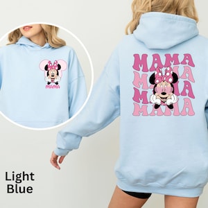 Puede incluir: Sudadera con capucha azul claro con un gr&aacute;fico de Minnie Mouse y la palabra "MAMA" en rosa. La parte delantera de la sudadera con capucha muestra a Minnie Mouse, y la parte trasera tiene un dise&ntilde;o "MAMA" apilado. Prenda casual y c&oacute;moda.