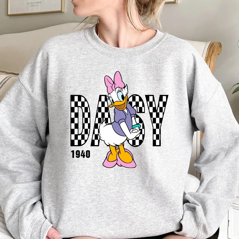 May include: Gray sweatshirt with a checkered black and white graphic of Daisy Duck with the word "DAISY" in the graphic and the number "1940" below the graphic.