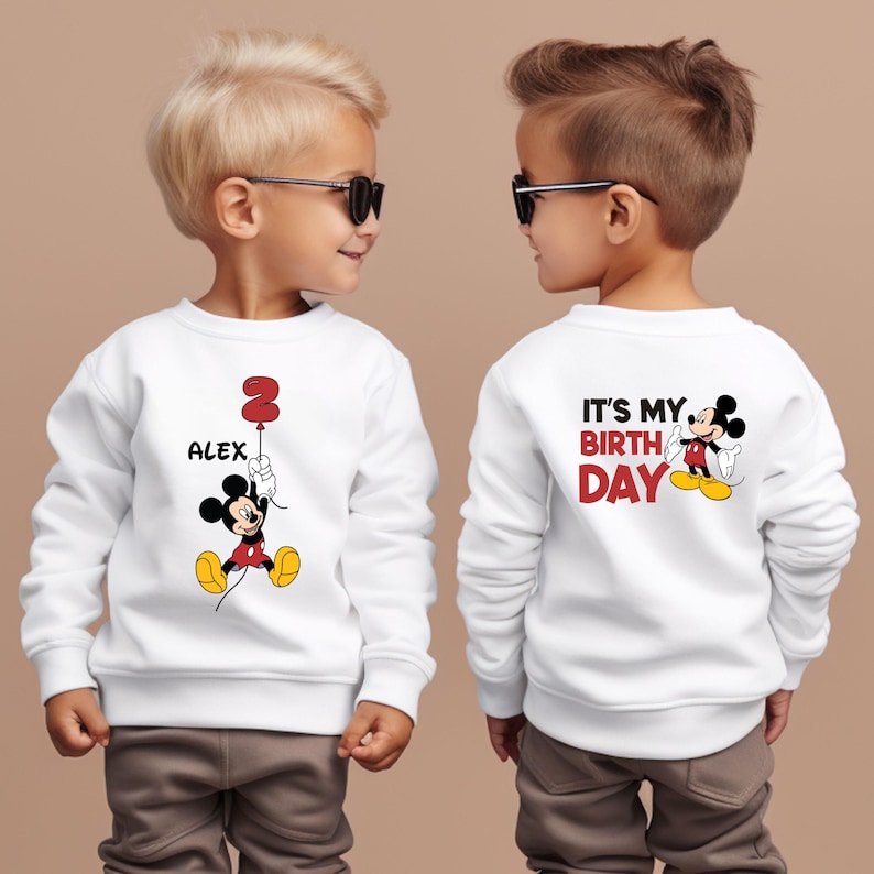 Puede incluir: Dos sudaderas blancas con un dise&ntilde;o de Mickey Mouse. Una sudadera dice "Es mi cumplea&ntilde;os" y la otra dice "Alex" con un globo n&uacute;mero 2.