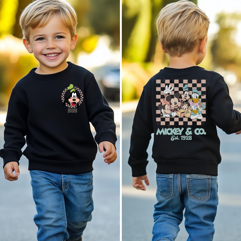 May include: A black sweatshirt with a checkered pattern on the back. The back of the sweatshirt features a graphic of Mickey Mouse and friends with the text "Mickey & Co. Est. 1928". The front of the sweatshirt features a graphic of Goofy with the text "Disney".