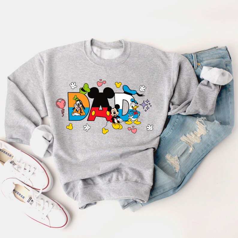 May include: A gray sweatshirt with a graphic print of Mickey Mouse, Donald Duck, and Goofy spelling out "DAD". The graphic is surrounded by hearts, stars, and handprints.