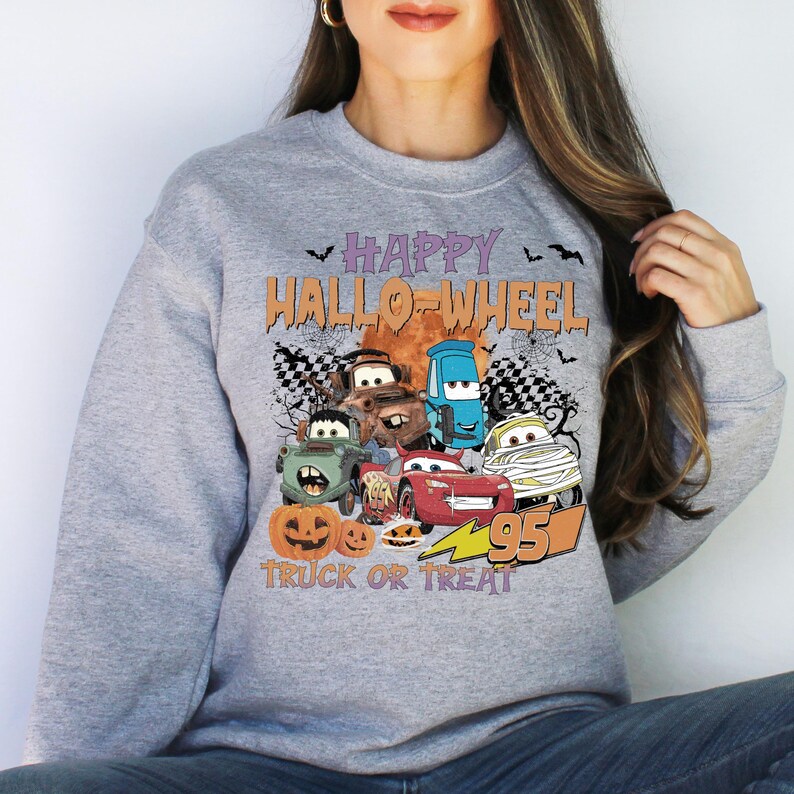 May include: Gray sweatshirt with a graphic of cartoon cars dressed up for Halloween. The text reads "Happy Hallo-Wheel Truck or Treat" with a pumpkin and the number 95.