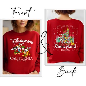 May include: Red Disneyland sweatshirt with a graphic of Mickey Mouse, Donald Duck, Goofy, and other Disney characters. The front of the sweatshirt says "Disneyland California EST 1955". The back of the sweatshirt has a castle graphic and says "Disneyland EST 1955".
