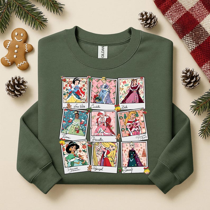 Puede incluir: Sudadera verde oscuro con nueve im&aacute;genes enmarcadas de princesas de Disney en entornos navide&ntilde;os festivos. Cada imagen es una foto estilo polaroid. Las princesas incluyen Blancanieves, Cenicienta, Bella, Tiana, Priscilla y otras.