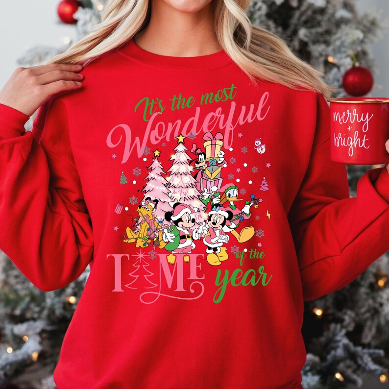 May include: Red Christmas sweatshirt with a festive design featuring Mickey Mouse and friends. The text reads "It's the most Wonderful Time of the Year".