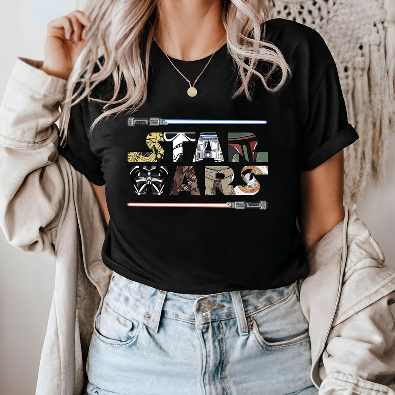 May include: Black t-shirt with a graphic of the Star Wars logo made up of characters from the movie. The logo is surrounded by two red lightsabers.
