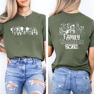 May include: Olive green t-shirt featuring a white graphic of cartoon characters on the front. The back of the shirt displays a group of characters with the text "Family Vacation" and the year "2026". The shirt is made of a soft material and is suitable for casual wear.