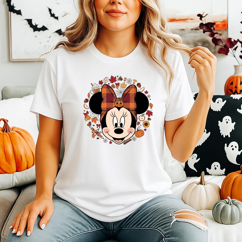 Puede incluir: Camiseta blanca con un dise&ntilde;o de Minnie Mouse con tem&aacute;tica oto&ntilde;al. El dise&ntilde;o incluye un lazo a cuadros, calabazas, hojas y otros elementos oto&ntilde;ales. La camiseta es de cuello redondo y manga corta.