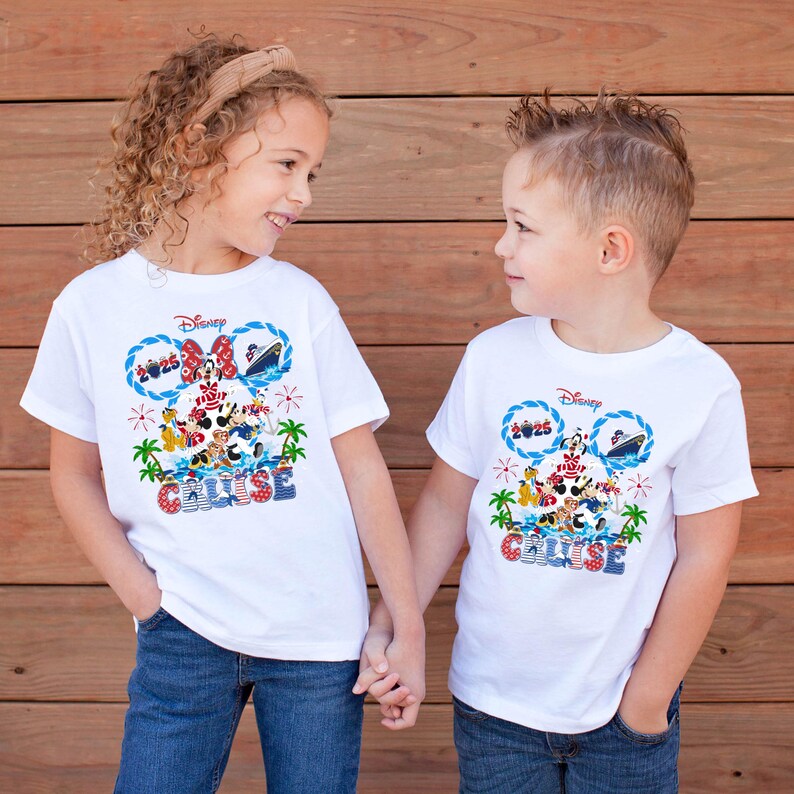 May include: Two children wearing white t-shirts with a Disney Cruise design. The shirts feature Mickey and Minnie Mouse, a cruise ship, and the word "CRUISE" in blue and red. The children are holding hands.