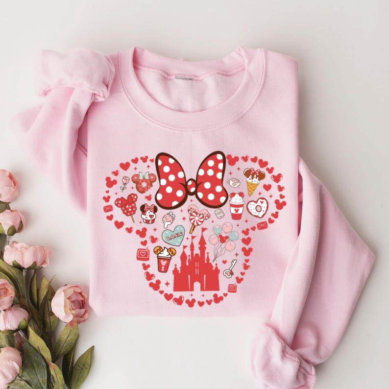 May include: Pink sweatshirt with a red and white bow and a graphic of Mickey Mouse's head filled with hearts, candy, and other Disney-themed imagery. The graphic includes the text "Love"