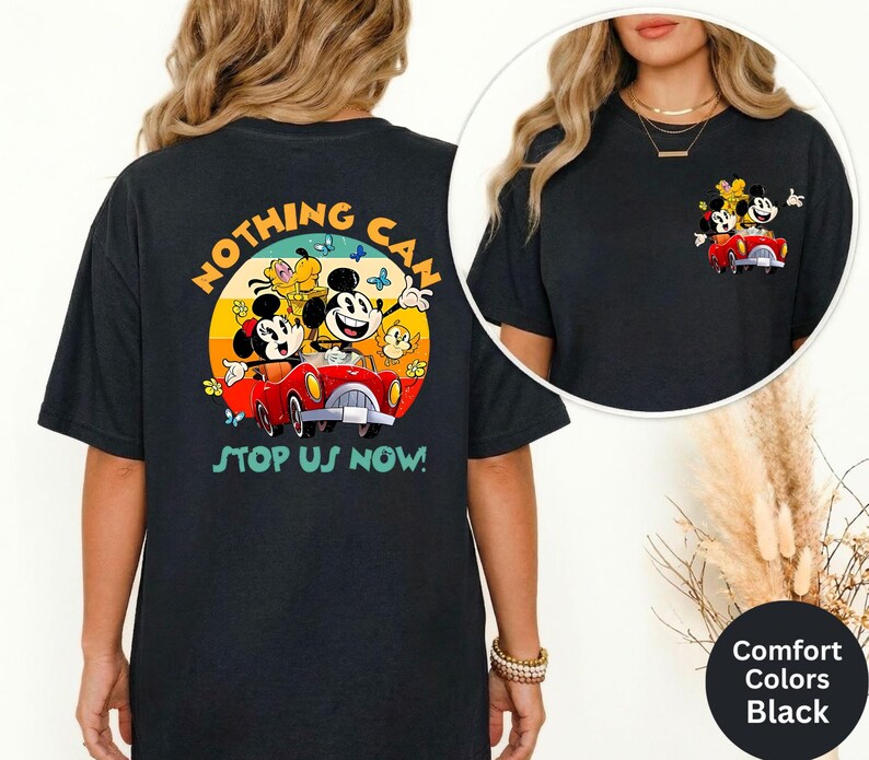 Pode incluir: T-shirt preto com um gr&aacute;fico colorido de Mickey e Minnie Mouse num carro vermelho, com o texto "NOTHING CAN STOP US NOW!". O design inclui um fundo de p&ocirc;r do sol amarelo e laranja. A t-shirt &eacute; da marca Comfort Colors.