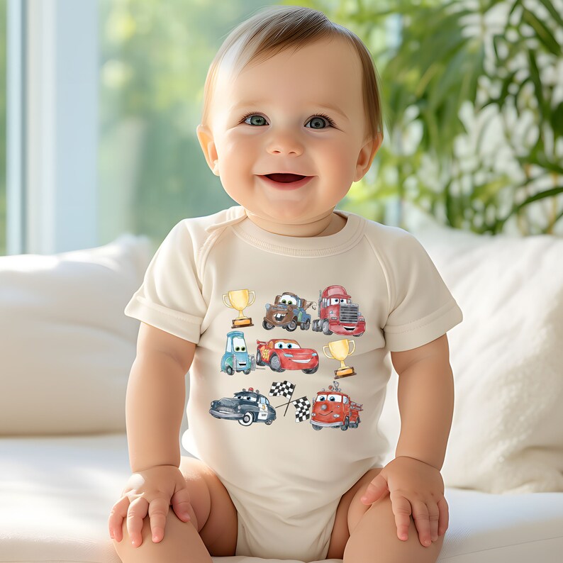 May include: A white baby onesie with a colorful cartoon design featuring various cars, including a red race car, a blue car, a brown truck, a red truck, and a fire truck. The design also includes a checkered flag and two gold trophies.