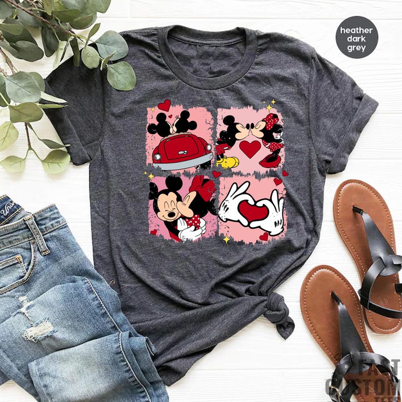 May include: A heather dark grey t-shirt featuring a graphic print of Mickey Mouse and Minnie Mouse in four different scenes. The scenes include Mickey and Minnie kissing, Mickey and Minnie driving a red car, Mickey and Minnie holding hands with a heart, and Mickey and Minnie kissing with a heart.