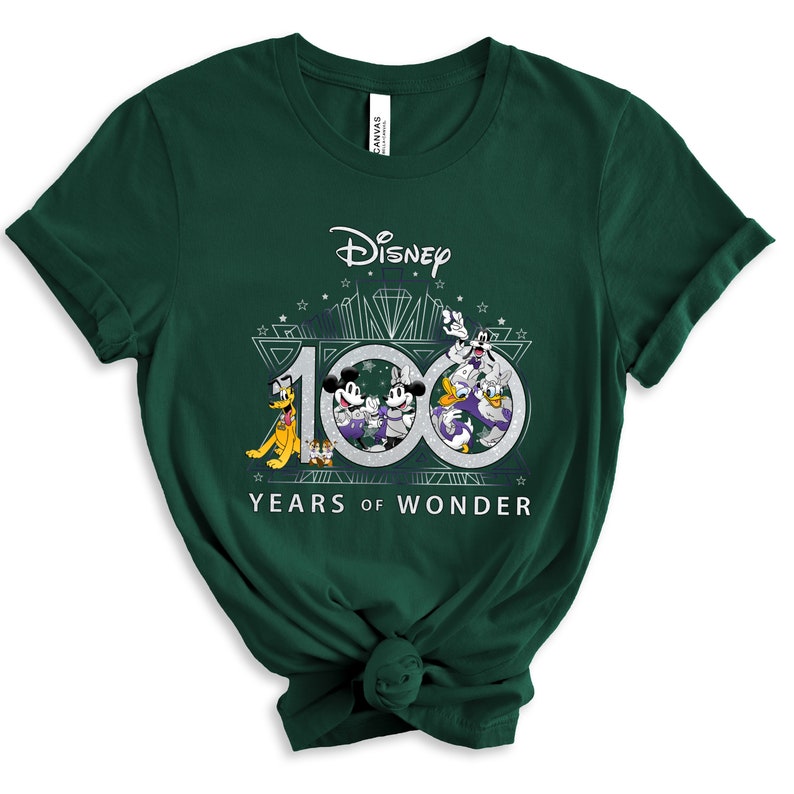 May include: A green t-shirt with a graphic of Mickey Mouse, Minnie Mouse, Donald Duck, Goofy, and Pluto celebrating Disney's 100th anniversary. The graphic includes the text "Disney" and "100 Years of Wonder".
