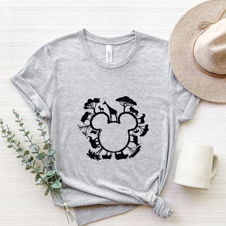 May include: A grey t-shirt featuring a black silhouette of Mickey Mouse's head. The silhouette is formed from animals and trees, creating a playful design.