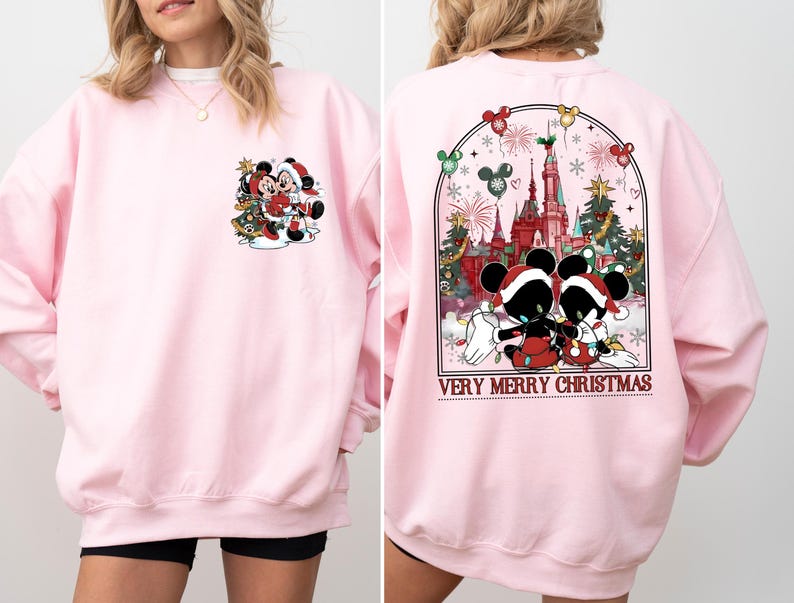 May include: Pink sweatshirt with a Christmas-themed design featuring Mickey Mouse and Minnie Mouse in front of a Christmas tree. The back of the sweatshirt has a design of Mickey Mouse and Minnie Mouse in front of a castle with the text "Very Merry Christmas".
