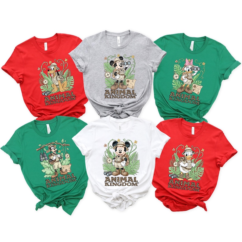 May include: A collection of six t-shirts in various colors: red, gray, green, and white. Each shirt features a different Disney character in safari attire with the words "Animal Kingdom" printed below the character.