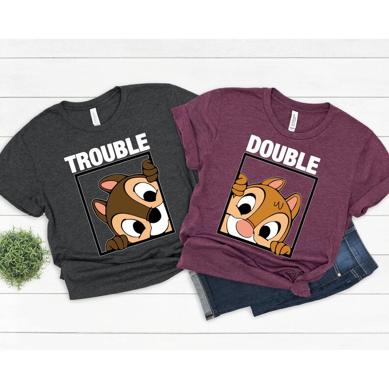 May include: Two t-shirts with a cartoon chipmunk peeking out of a frame. The gray shirt says "Trouble" and the maroon shirt says "Double".