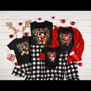 May include: A family of four matching Christmas pajamas with black and white plaid pants. The shirts feature a festive green and red design with Mickey Mouse, Minnie Mouse, and Donald Duck.