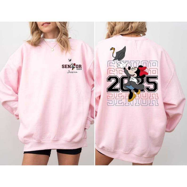 Puede incluir: Sudadera rosa con un gr&aacute;fico de Mickey Mouse con un gorro de graduaci&oacute;n y el texto "Senior 2025" en la espalda. La parte delantera de la sudadera tiene el texto "Senior 2025" y el nombre "Jessica" impreso en ella.