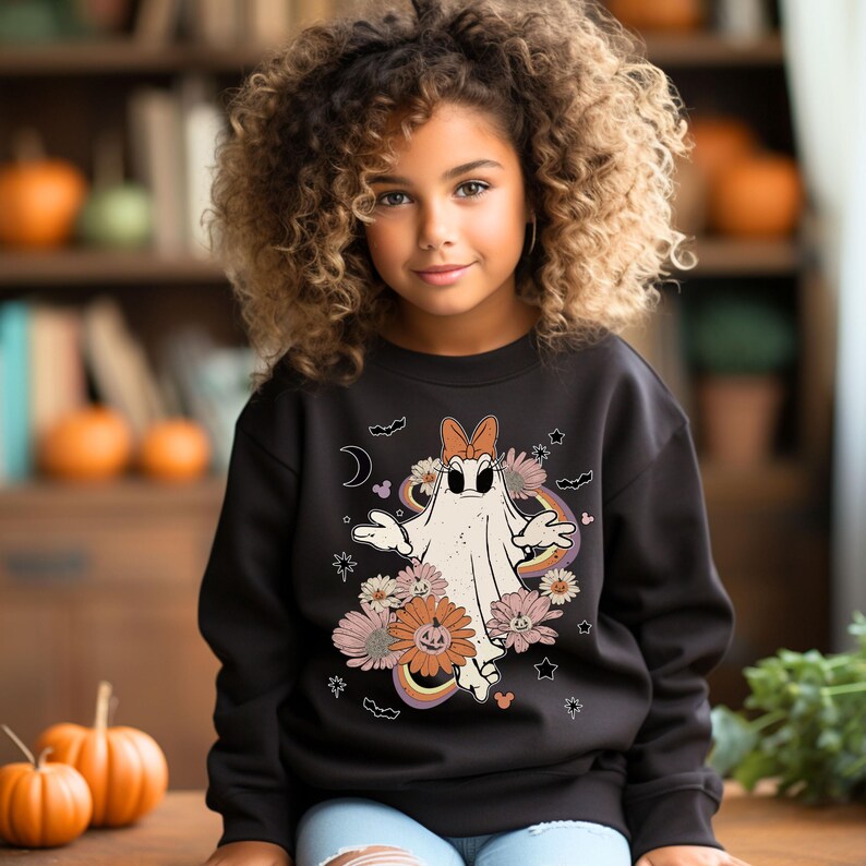 May include: Black sweatshirt with a white ghost wearing a bow and surrounded by flowers and stars. The ghost has a surprised expression and is holding its arms out. The text "Boo!" is printed on the sweatshirt.