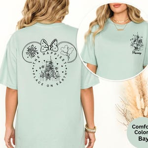 May include: A light green t-shirt with a black graphic of a castle, Mickey Mouse ears, and the text "THE HAPPIEST PLACE ON EARTH." A smaller graphic on the front says "Mommy."