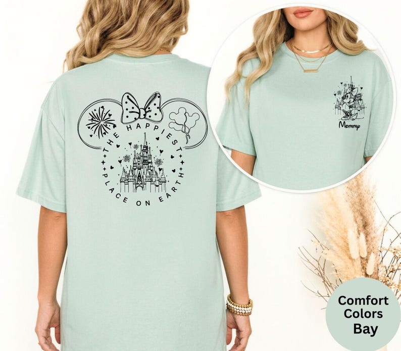 May include: A light green t-shirt with a black graphic of a castle, Mickey Mouse ears, and the text "THE HAPPIEST PLACE ON EARTH." A smaller graphic on the front says "Mommy."