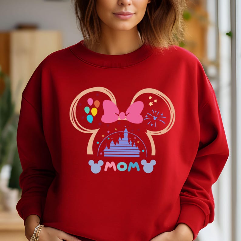 May include: Red sweatshirt with a graphic of Mickey Mouse ears, a bow, a castle, and the word "MOM" in a colorful design.