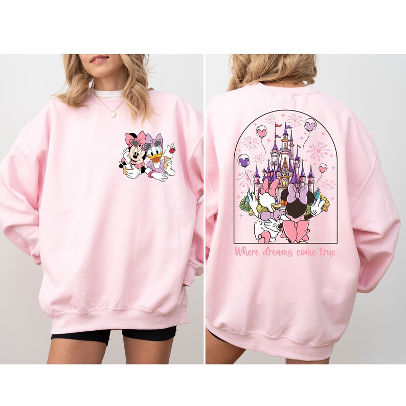 Pu&ograve; includere: Felpa rosa con un'immagine di Topolino e Minnie Mouse sul davanti e un'immagine del castello di Cenerentola con Topolino e Minnie Mouse sul retro. Il testo "Where dreams come true" &egrave; stampato sotto l'immagine del castello.