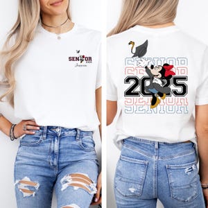 Puede incluir: Camiseta blanca con un gr&aacute;fico rojo, blanco y azul de Mickey Mouse con un gorro de graduaci&oacute;n y el texto "Senior 2025". La camiseta tambi&eacute;n tiene el texto "Senior 2025" repetido en un dise&ntilde;o apilado en la parte posterior.