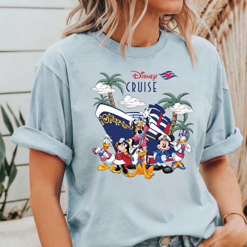Pu&ograve; includere: Maglietta blu chiaro con una grafica di Topolino e i suoi amici su una nave da crociera Disney. Il testo "Disney Cruise" &egrave; stampato sulla maglietta.