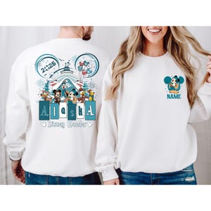 May include: White long-sleeve shirts with a Disney cruise theme. The back of one shirt features a graphic of Mickey Mouse and friends with the text "Alaska" and "Disney Wonder". The front of the other shirt features a graphic of Mickey Mouse with the text "NAME".