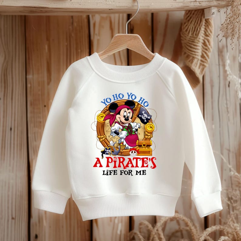 K&ouml;nnte beinhalten: Wei&szlig;er Langarm-Sweatshirt mit einem Cartoon-Bild von Mickey Mouse, der als Pirat verkleidet ist. Der Text "Yo ho yo ho A Pirate's Life For Me" ist auf dem Shirt aufgedruckt.