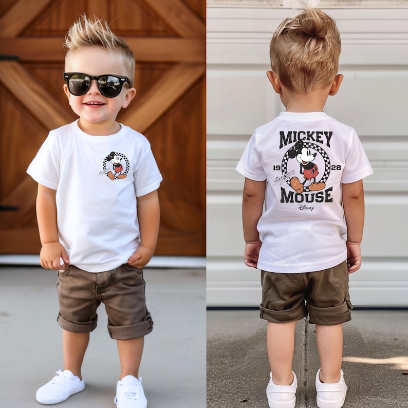 May include: Two toddler boys model matching olive green shorts and white t-shirts. One shirt features a Mickey Mouse graphic on the front, the other has 'Mickey Mouse' printed on the back with a Mickey Mouse graphic.  Both shirts have '1928' and 'Disney' printed on them.