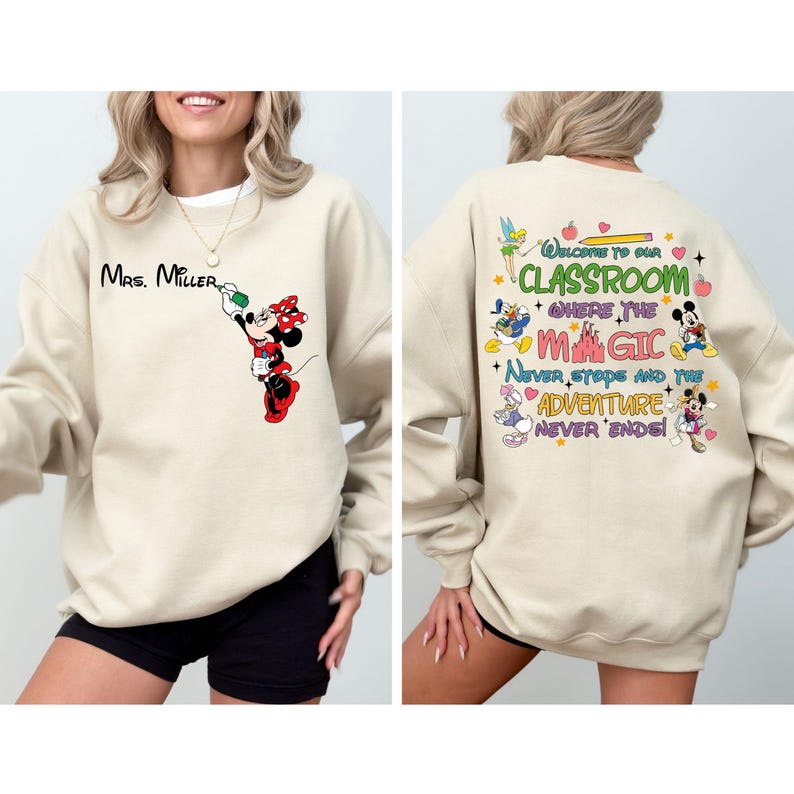 May include: Beige sweatshirt with a Mickey Mouse character design on the front and a colorful graphic with the text "Welcome to our classroom where the magic never stops and the adventure never ends!" on the back.