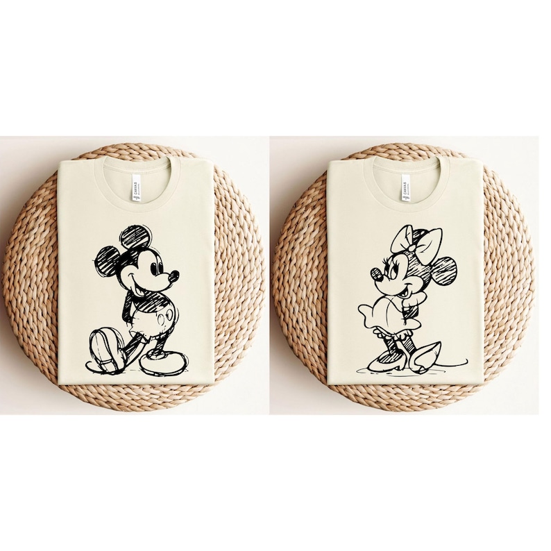 May include: Two cream-colored t-shirts with black and white cartoon images of Mickey Mouse and Minnie Mouse. The images are in a sketch style.