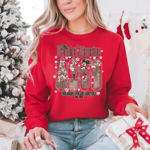 May include: Red Christmas sweatshirt with a graphic of the Haunted Mansion characters from Disney. The text on the sweatshirt reads "The Haunted Mansion Welcome Foolish Mortals Est. 1969".