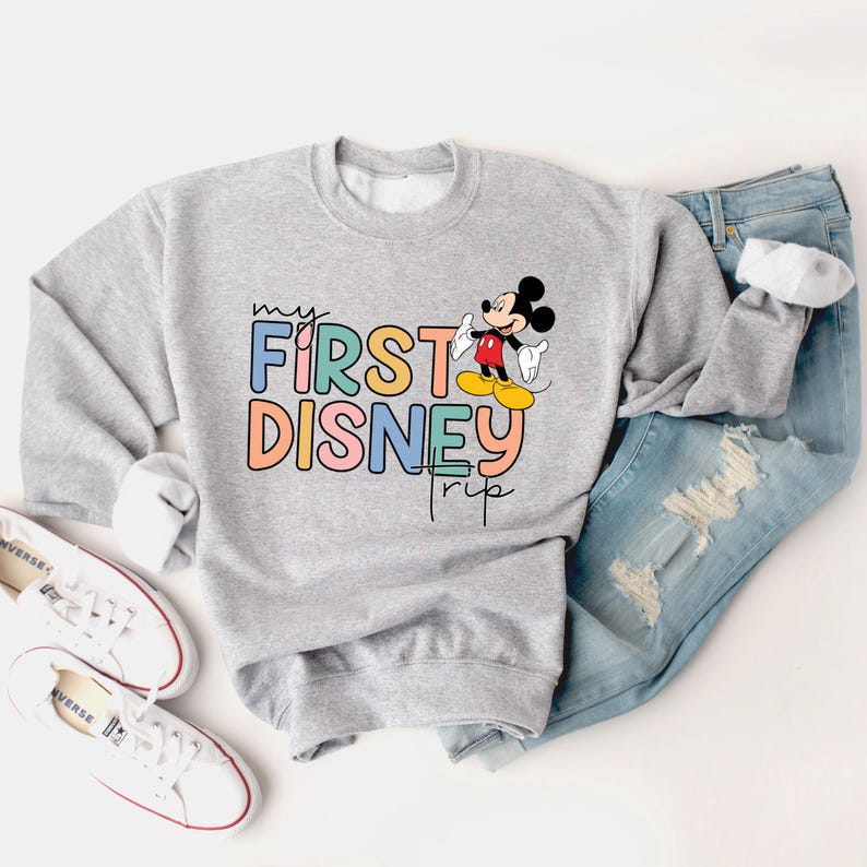May include: A gray sweatshirt with a colorful "My First Disney Trip" graphic and a cartoon image of Mickey Mouse.
