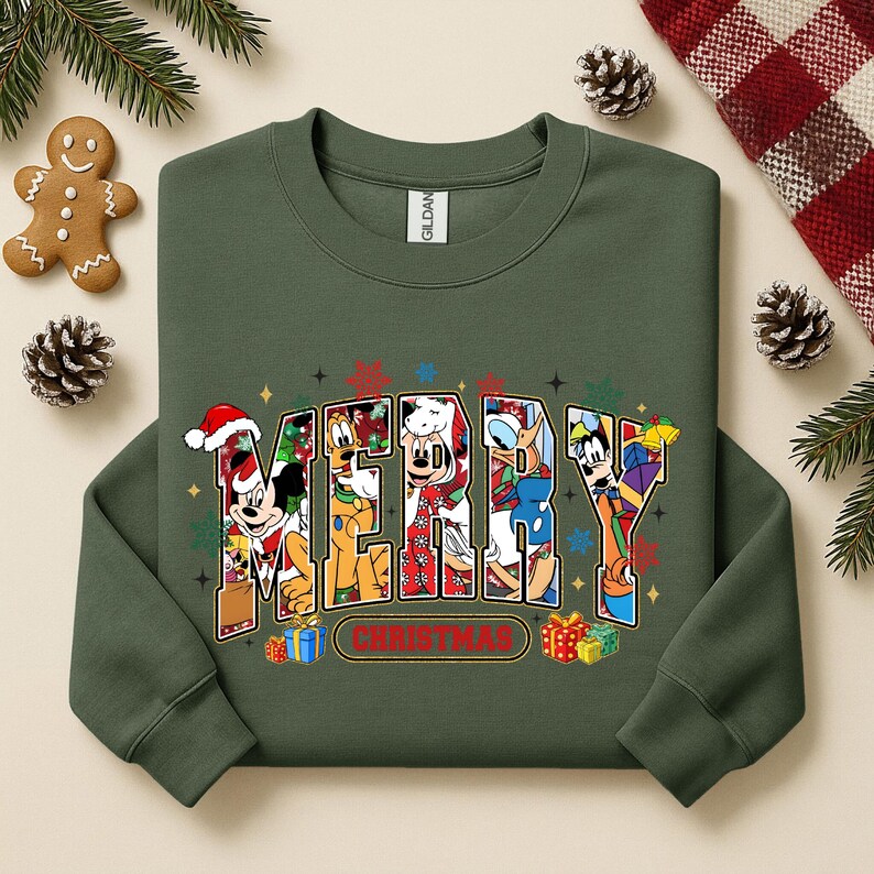 May include: A dark green sweatshirt with the word "MERRY CHRISTMAS" in a colorful, cartoon-style design. The letters are filled with images of Disney characters. Presents and snowflakes surround the text.