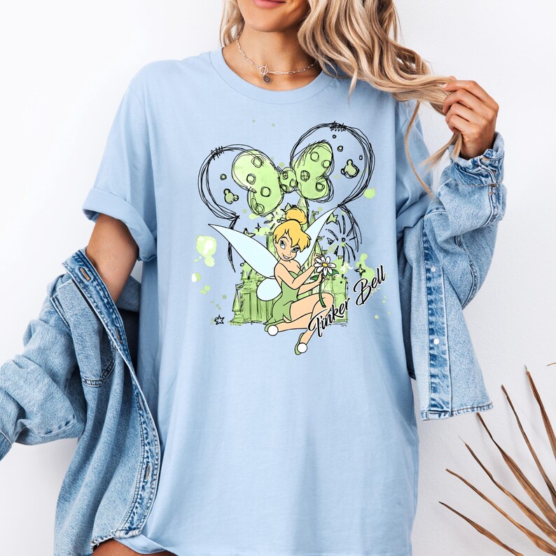 May include: Light blue t-shirt with a graphic of Tinker Bell, a green bow, and the text "Tinker Bell".