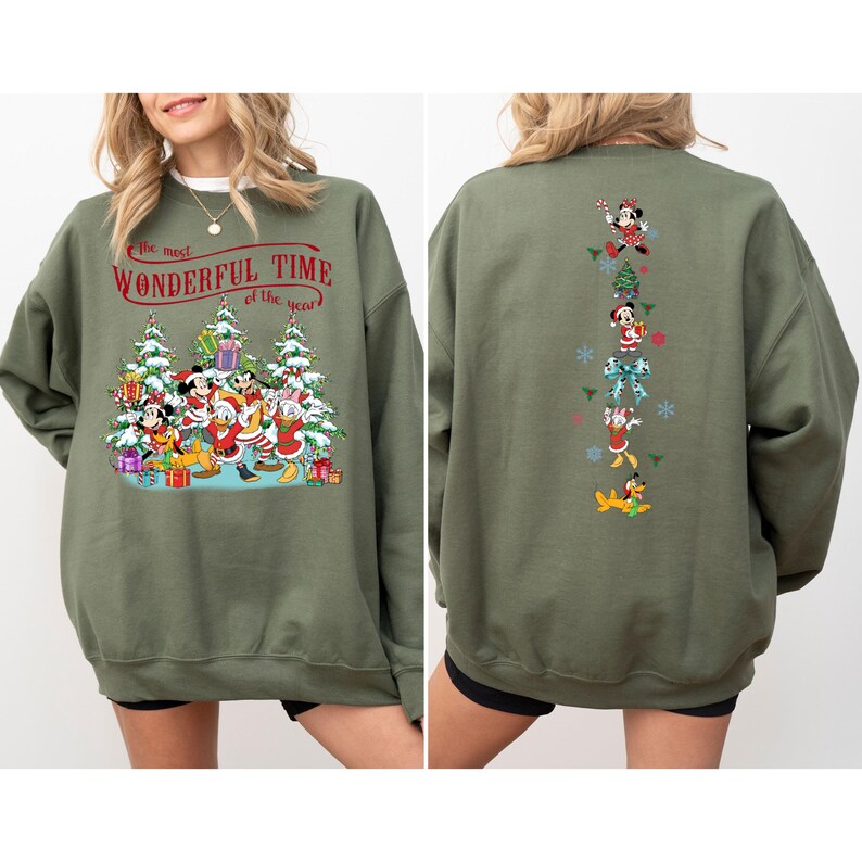 Puede incluir: Sudadera verde oliva con un dise&ntilde;o navide&ntilde;o. La parte delantera muestra personajes de Disney con atuendos festivos con el texto "the most Wonderful Time of the Year". La parte posterior tiene gr&aacute;ficos de personajes.