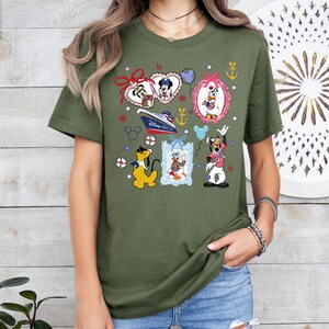 Puede incluir: Camiseta verde con un estampado colorido de personajes de Disney, incluyendo Mickey Mouse, Minnie Mouse, Donald Duck, Goofy y Pluto. El estampado presenta un crucero, anclas, estrellas y corazones. "Disney Cruise Line" est&aacute; escrito en el barco.